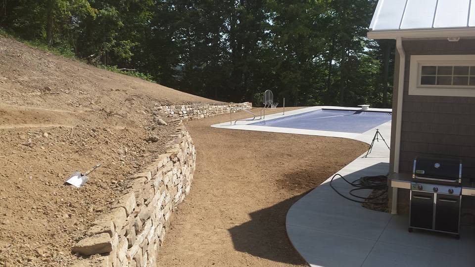 Poolside slope with fresh stone retaining wall before seeding